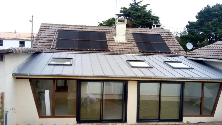 Couverture en zinc équipée de panneaux solaires et de fenêtres de toit